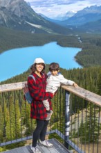 Mother holding her son while admiring the stunning panoramic view of vibrant turquoise waters at