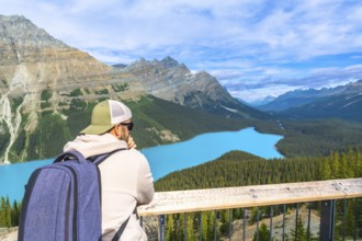 Tourist with backpack is enjoying the breathtaking panoramic view of the turquoise peyto lake and