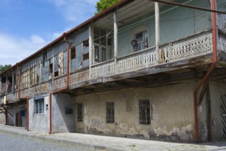 Elongated balcony of an old building with weathered wooden railings under a clear blue sky,