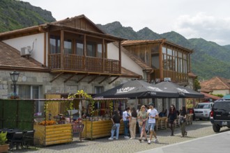 Tourists discover market stalls in front of traditional wooden buildings in mountainous