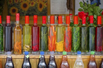 Strung bottles with colorful liquids on a wooden counter, chacha with colorful fruits, vegetables