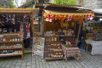 Market stalls with handmade souvenirs and decorations surrounded by flags and autumn leaves,