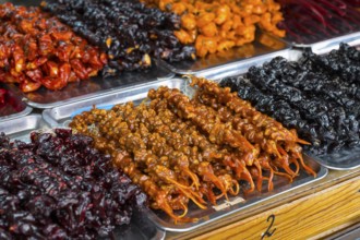 Plates of colorful Georgian sweets made from fruits and nuts at a market stand, Churchkhela,
