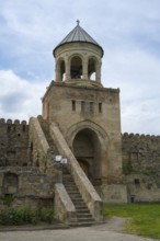 A bell tower with stone steps and fortress under a cloudy sky, Svetitskhoveli Cathedral,