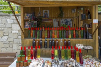 Market stall with various colorful bottles, food and souvenirs on a table, chacha with colorful