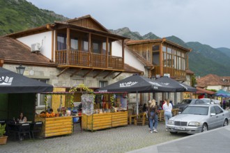 Cosy marketplace with cafes and shops framed by mountains under a cloudy sky, houses on Mtskheta