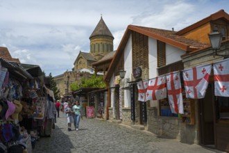 Street with souvenir stands, Georgian flags and a church in the background, Svetitskhoveli