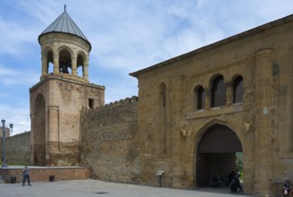 A historic bell tower and fortress walls under cloudy sky, Svetitskhoveli Cathedral,