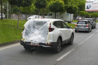 A car drives on the road with plastic wrap over the rear, Tbilisi, Mtskheta-Mtianeti region,