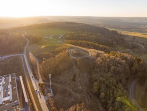 Aerial view of hilly landscape and forest in evening light, future PV building on old deposit,