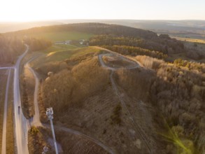 Evening landscape with hills, roads and extensive forests in soft light, future PV construction on