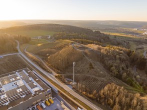Telecommunication tower over hilly landscape and industrial buildings in the evening light, future