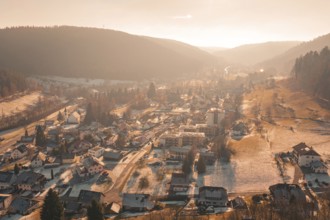 Expansive view of a village in peaceful, snowy hills at sunset, Enzklösterle, Calw district,