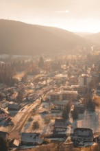 Aerial view of a snowy village in a hilly landscape illuminated by the warm winter sun,