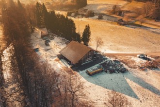 Evening winter landscape with a building surrounded by snow-covered fields and trees, Enzklösterle,