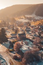 Idyllic view of a village with a central church surrounded by snow-covered houses and hills,
