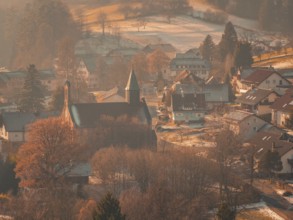 A small village with a church and snowy roads, nestled in a quiet, wintry environment,