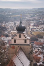 View of a church tower in front of a snow-covered city panorama with vast fields, Herrenberg,