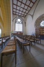 Church interior with rows of chairs and Gothic windows, quiet and devotional atmosphere, collegiate