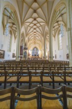 Symmetrical view along the rows of benches in the nave with Gothic columns and high ceilings,