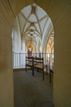 View through an arch of seats in a church with Gothic arches, quiet atmosphere, collegiate church,