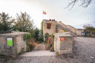 A historic castle wall with a waving flag and people enjoying the autumn view, Herrenberg,