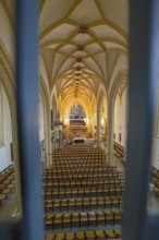 Symmetrical view of a church interior with altar and chairs, characterized by Gothic style,