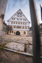 Large half-timbered house with symmetrical façade and grid in the foreground in a historic old