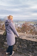 Woman in a coat looking out over a quiet winter landscape with a wide view, Herrenberg, Böblingen