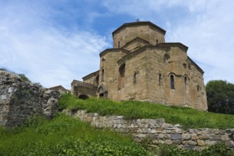 Stone church with grass-covered wall under blue sky, Javari Monastery, Jvari Monastery, Dzhwari