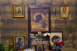 Religious icons on a stone wall with flower arrangement and candles, Javari Monastery, Jvari