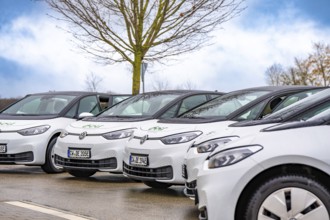 White electric cars park under a blue sky with bare trees, ID3, Deer E-Carsharing, Germany