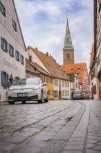 Paved alley in charming old town district with church tower, ID3, deer e-car sharing, Germany