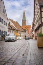 Narrow paved alley in historic old town with church tower, ID3, deer e-car sharing, Germany