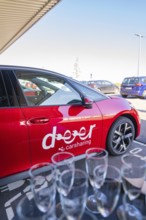 Red car sharing car in parking lot with glasses in the foreground, sunny weather and city