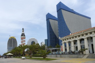 Skyscrapers with blue glass facades next to palm trees and column-supported buildings shape the