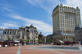 Open square with tall buildings and market stalls under a cloudy sky, Royal Casino and Hotel on the