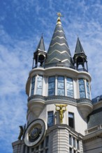 Close-up of a tower with a golden statue and ornate architectural details, astronomical clock,