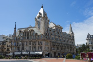 Large building with towers and roof gables in a sunny public square, Europe Square, Batumi, Black