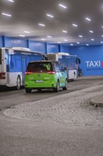 Interior view of a bus stop with green shuttle and buses, urban atmosphere, Deer E-Mobility Shuttle