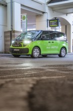 Green shuttle at a covered stop, quiet urban area, Deer E-Mobility Shuttle Service, Calw, Germany