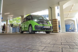 Green VW under roof in urban environment, Deer E-Mobility Shuttle Service, Calw, Germany