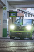 Green VW with lights on at a bus stop at night, Deer E-Mobility Shuttle Service, Calw, Germany
