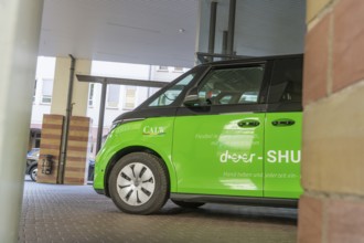 Green car in a parking lot, modern and stylish under canopy, Deer E-Mobility Shuttle Service, Calw,