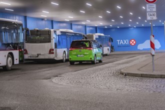 Bus station with green shuttle and taxi signs, urban scene at night, Deer E-Mobility Shuttle