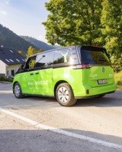 Green car on road in picturesque landscape with mountains in the background, Deer E-Mobility