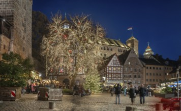 Christmassy illuminated square with the historic Pilate House with advent calendar, in the evening