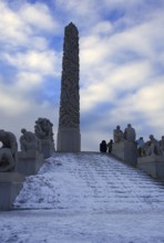 Large monolith surrounded by sculptures and a snowy staircase, Vigeland Sculpture Park Oslo Norway