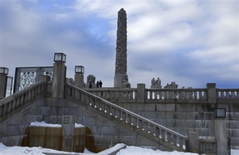 Monolith and statues on snowy stairs, cold winter atmosphere, Vigeland sculpture park Oslo Norway