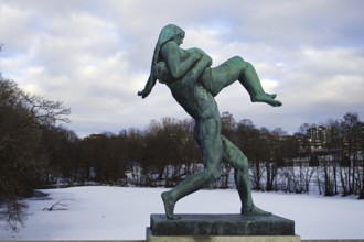 Bronze statue of a man carrying a woman. Winter landscape, icy river in the background, Vigeland